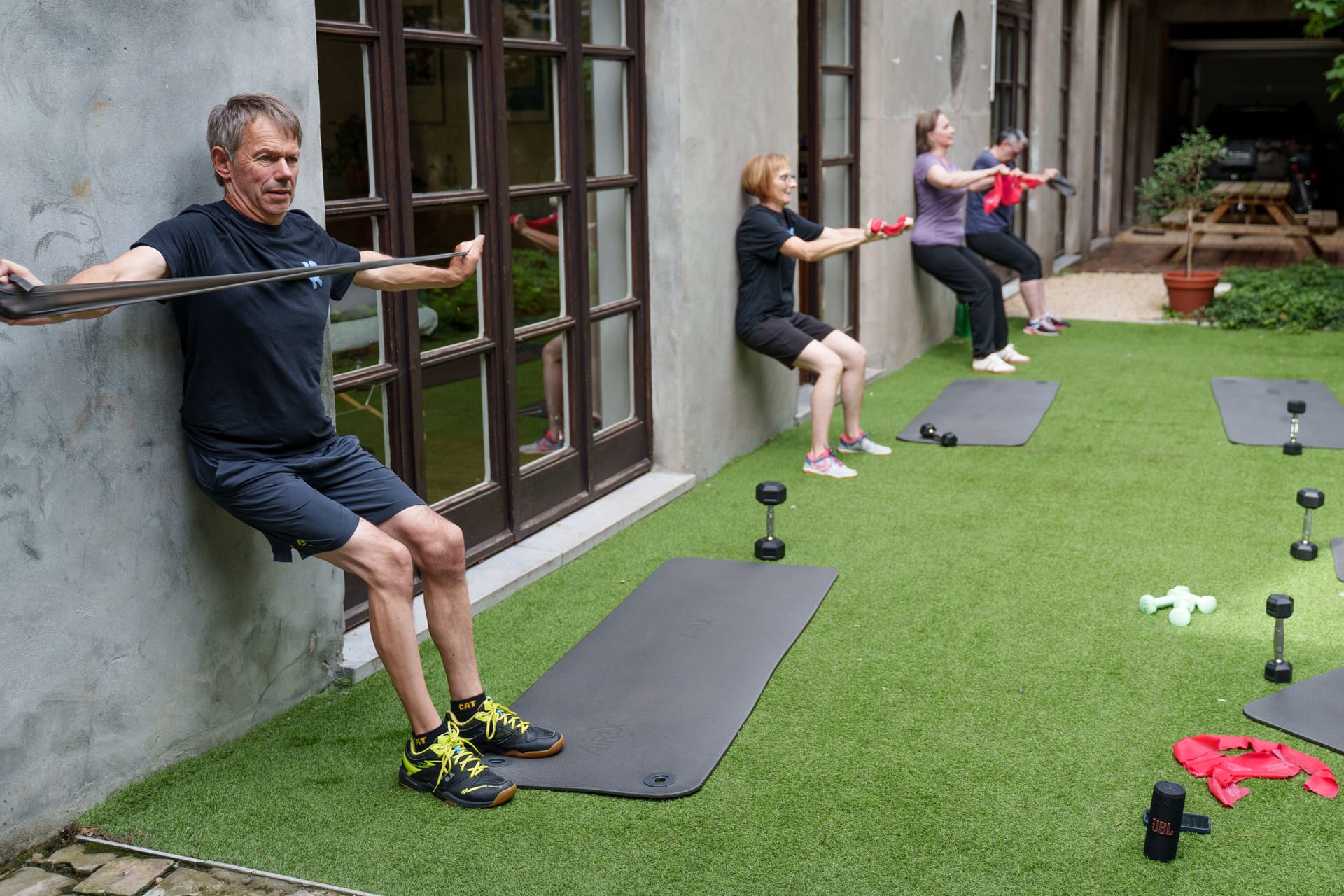 Deelnemers trainen met elastieken tegen de muur van de binnenkoer