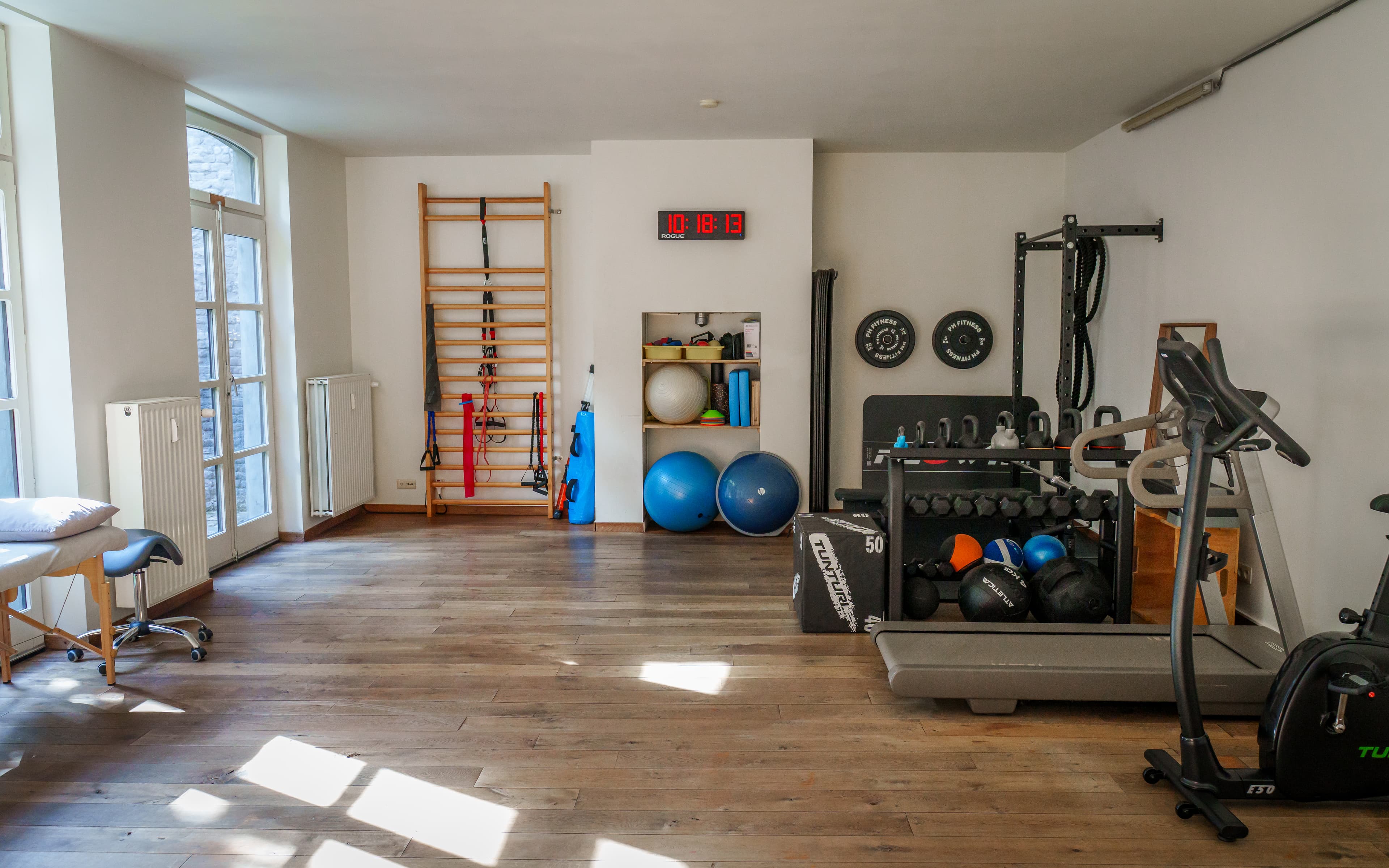 Oefenzaal met wandrek, hometrainer en gewichten in de praktijk in Gent
