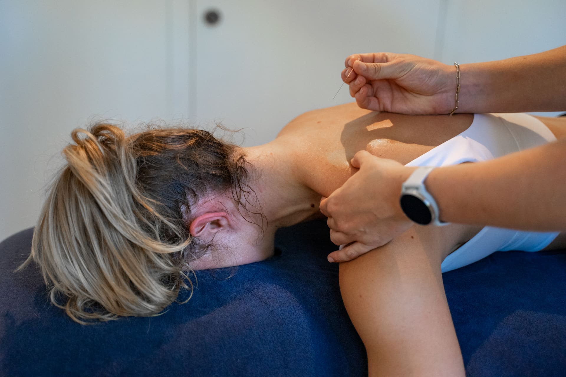 Kinesitherapeut behandelt de schouder- en nekspieren van een patiënt met dry needling