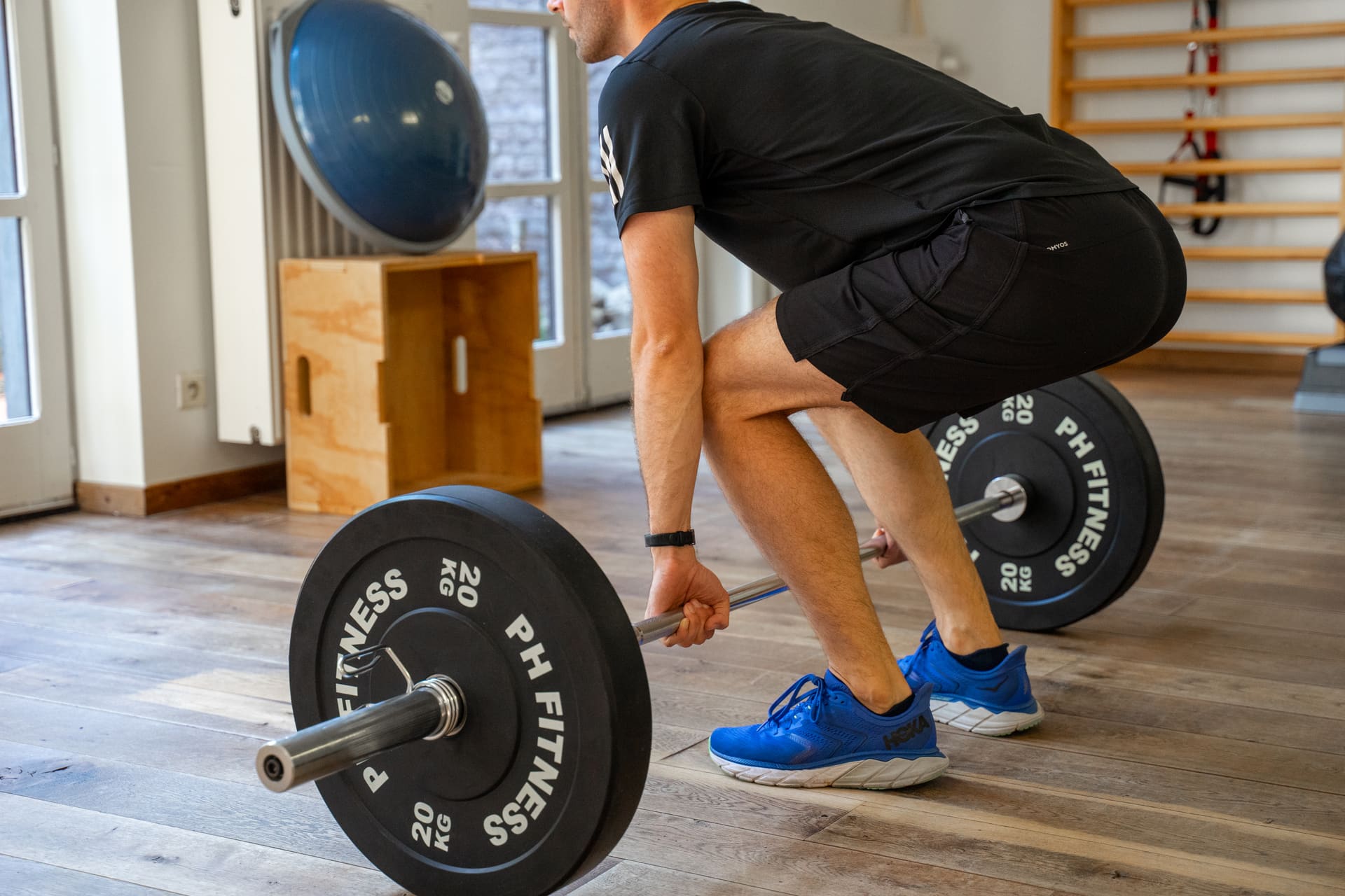 Sporter neemt de startpositie in voor een deadlift onder begeleiding